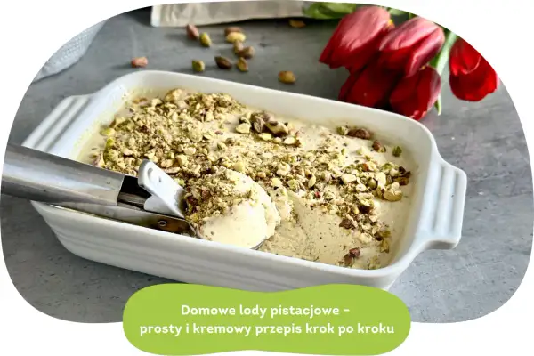 Kremowe lody pistacjowe w białej misce, posypane posiekanymi pistacjami. Obok czerwone tulipany.