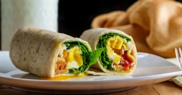 Pyszna tortilla z jajkiem, chrupiącym boczkiem i świeżą sałatą. Idealna na śniadanie lub szybki lunch.