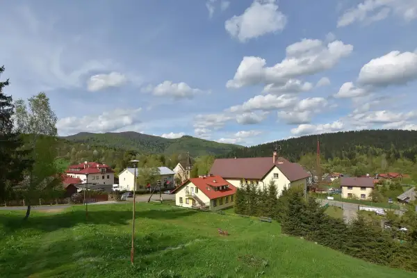Widok na Cisną z zielonymi wzgórzami i budynkami. Idealne miejsce na rodzinne wakacje, oferujące liczne cisna atrakcje dla dzieci.